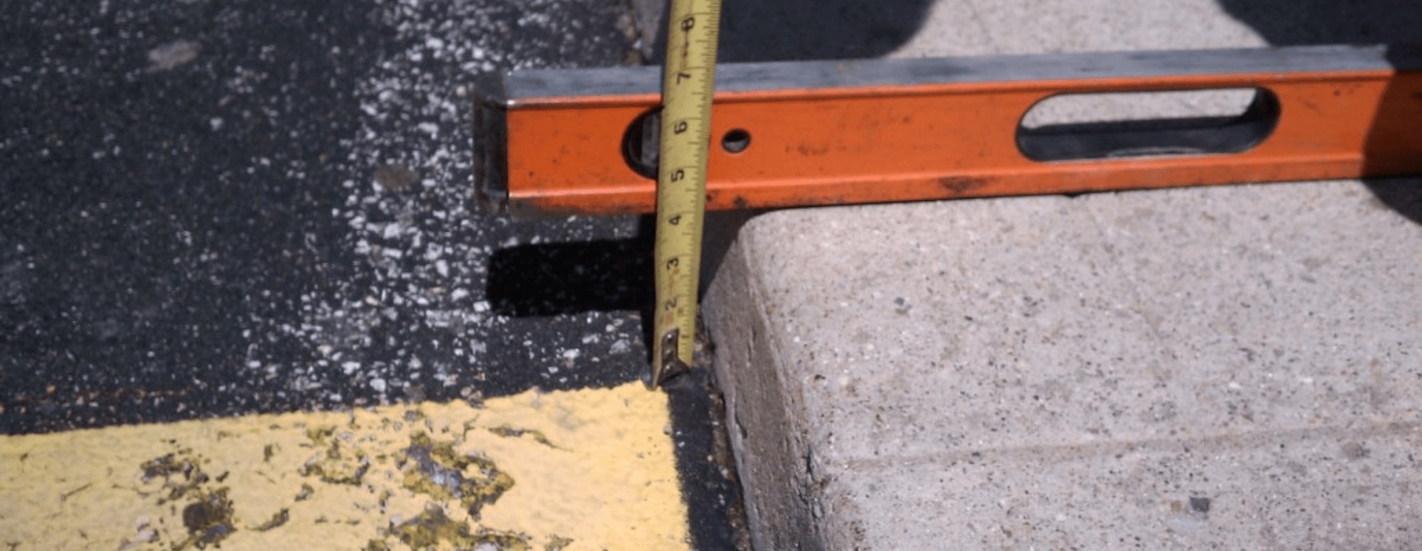 RMA surveyor checking a curb grade with a level and tape